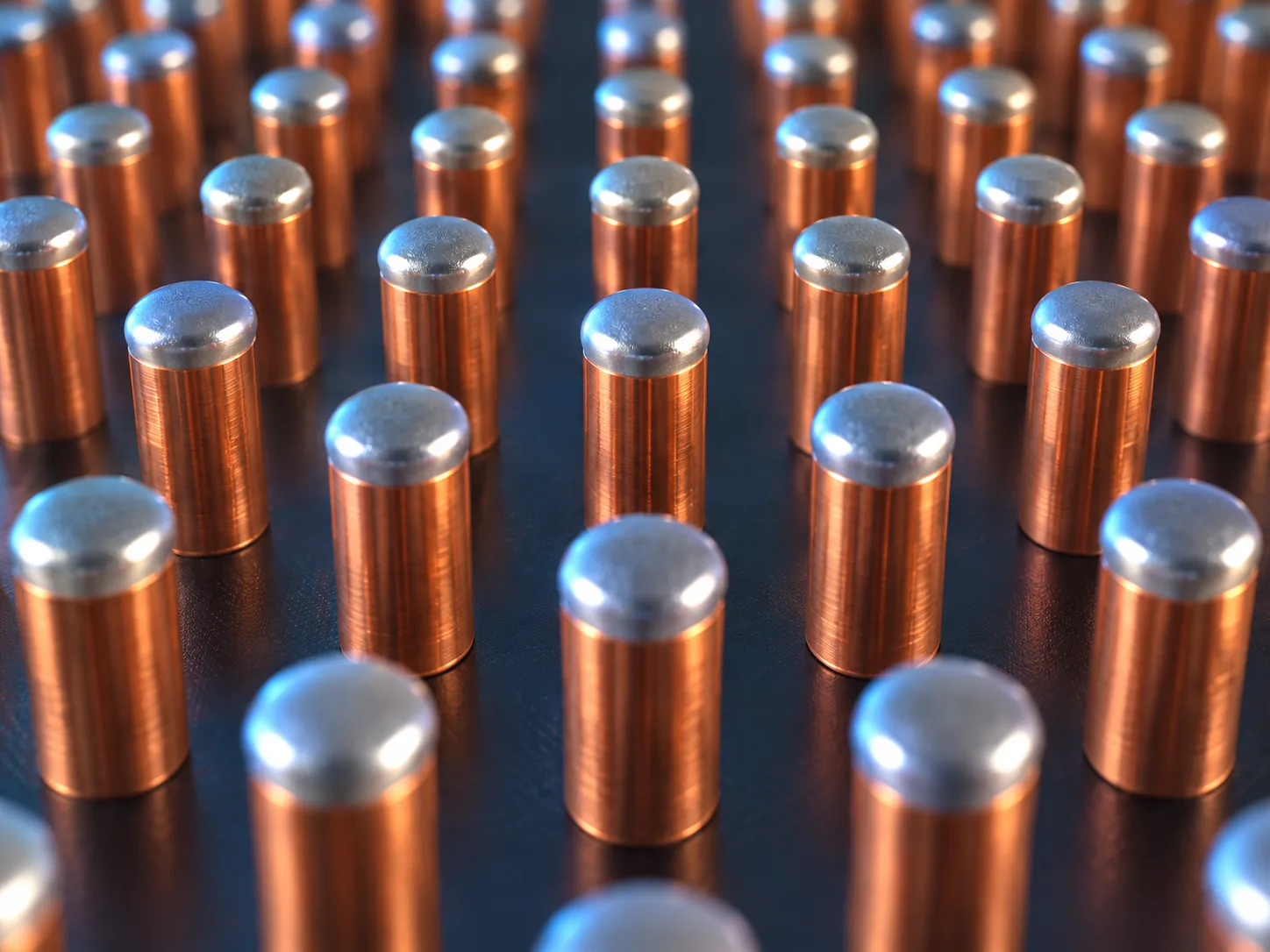 Magnified conceptual image of slender copper-coloured cylinders standing in neat rows on the underside of a semiconductor chip, with silver solder only on their tips