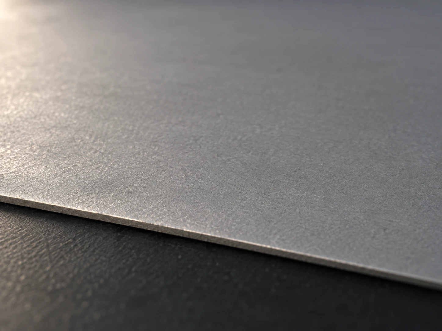 Conceptual image of the thin even surface of a sheet pressed from powder, lit at a low angle on a dark surface