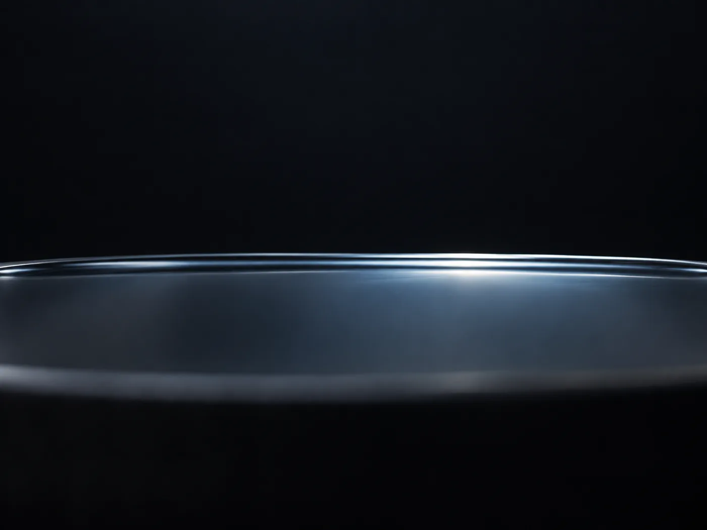 Conceptual image of the surface of a clear liquid with a faint milky tint, softly scattering light against a dark background