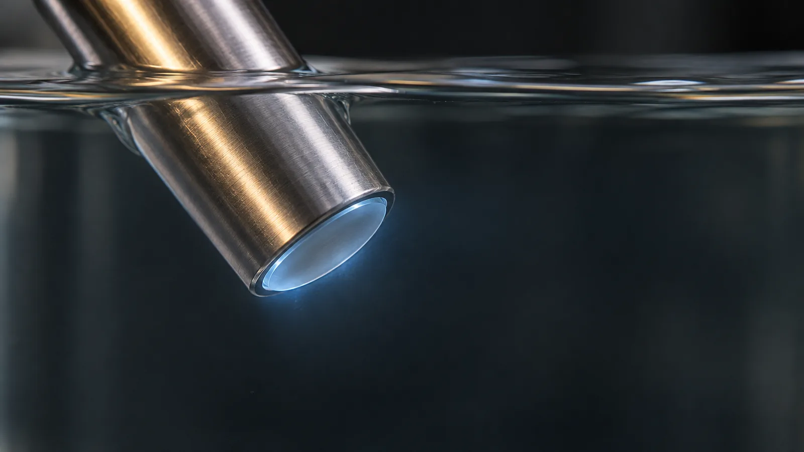 Conceptual image of the faintly glowing tip of a plain cylindrical optical probe inserted into a clear liquid