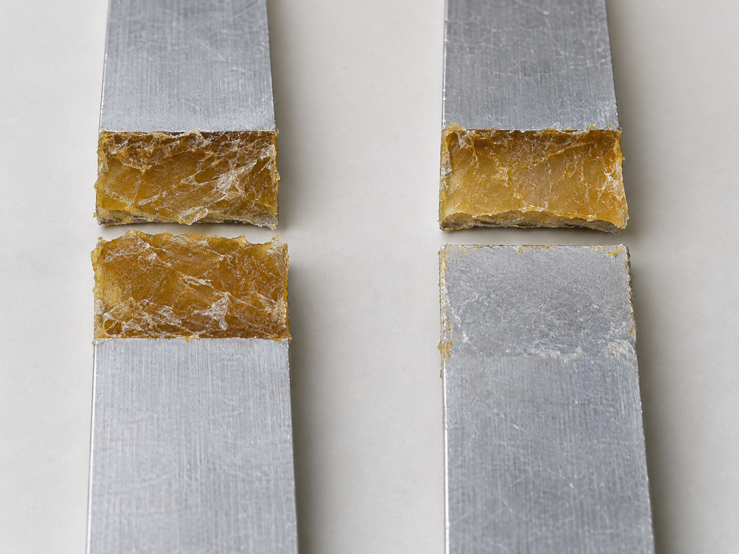 Fig. 4: two specimen pairs after a lap-shear test — fracture surfaces of cohesive and adhesive failure